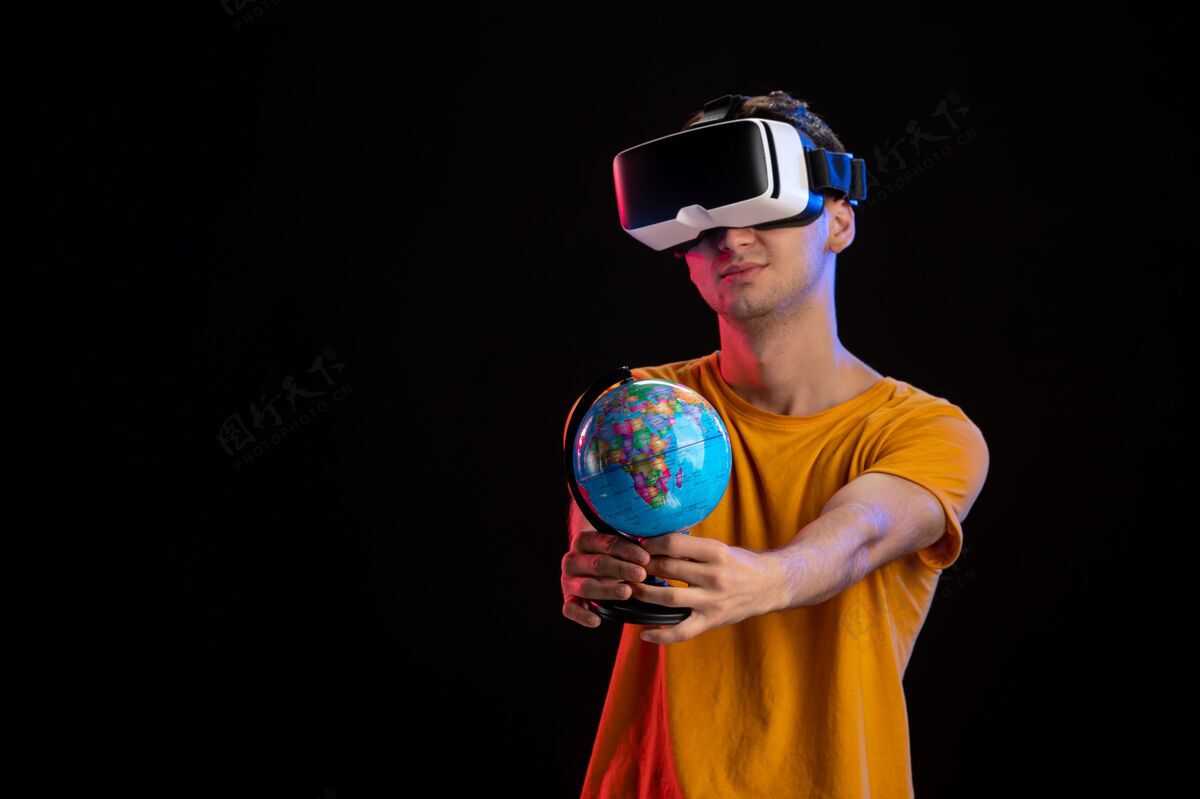 地球在黑暗的表面上玩虚拟现实拿着地球仪的年轻男性世界现实玩家