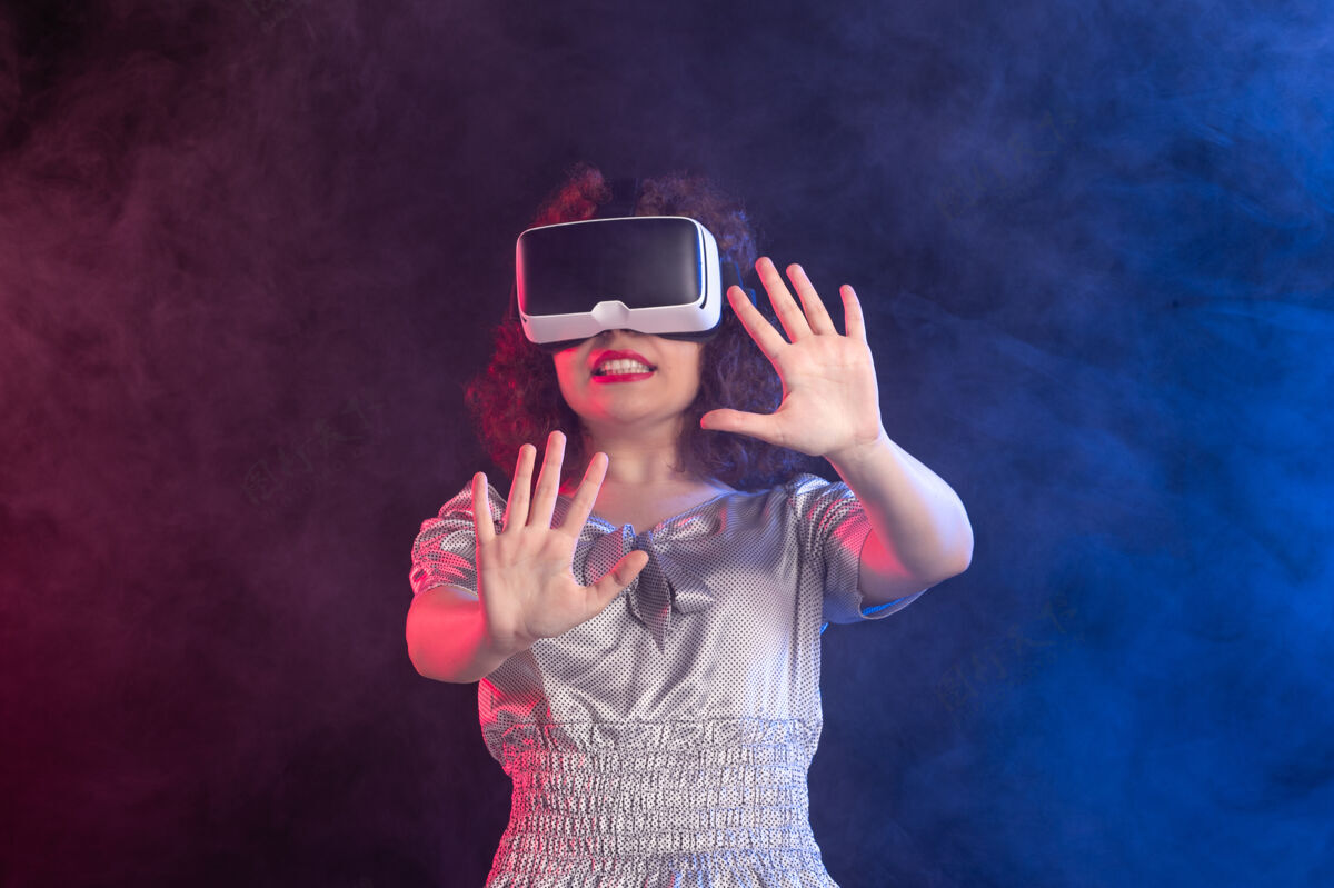 人物年轻女性戴着虚拟现实耳机在深蓝色的表面现实虚拟游戏