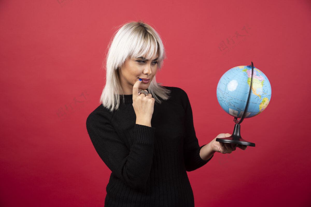 人在红色背景上与地球仪合影的年轻女子高质量照片地球女人肖像