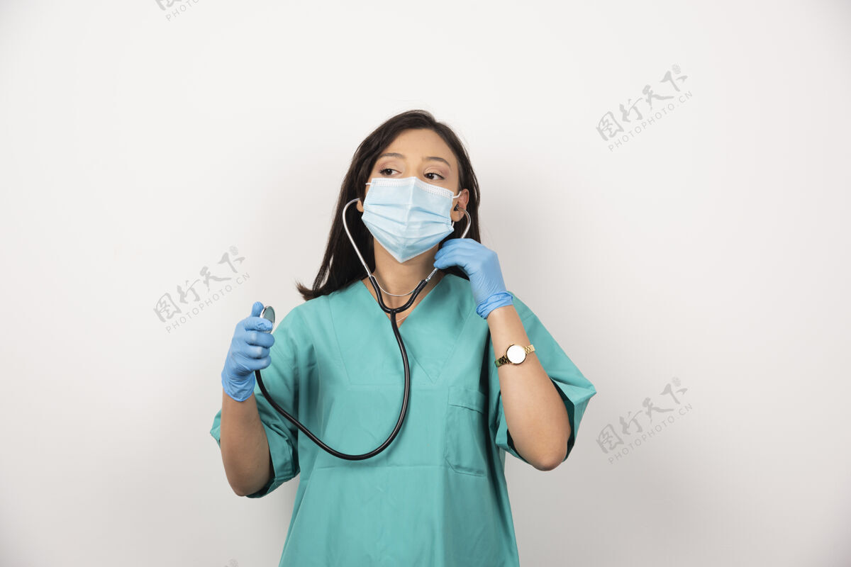 站立戴着面具的女医生在白色背景上展示她的肌肉高质量的照片医疗医生阳性