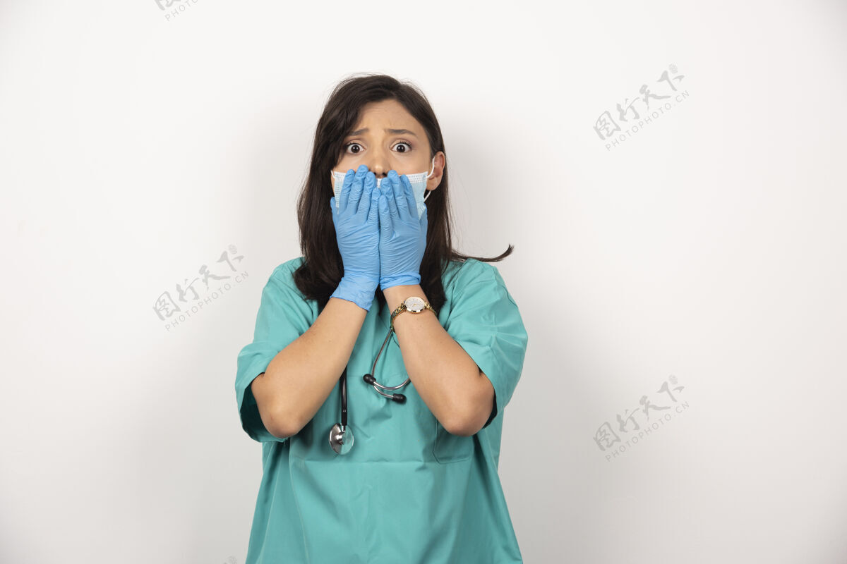面罩戴着医用口罩和手套的年轻医生在白色背景上把脸托着高质量的照片医生女性妇女