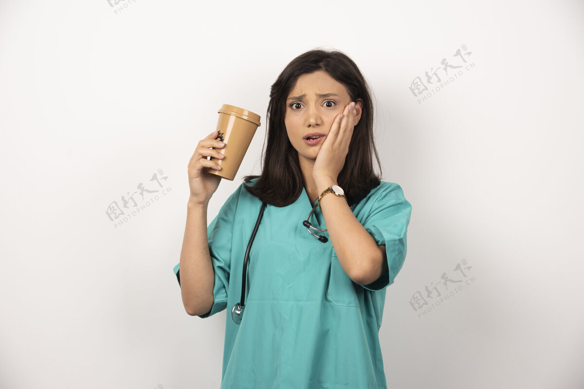 持有女医生拿着一杯咖啡托着白色背景的脸颊高质量的照片听诊器咖啡保健