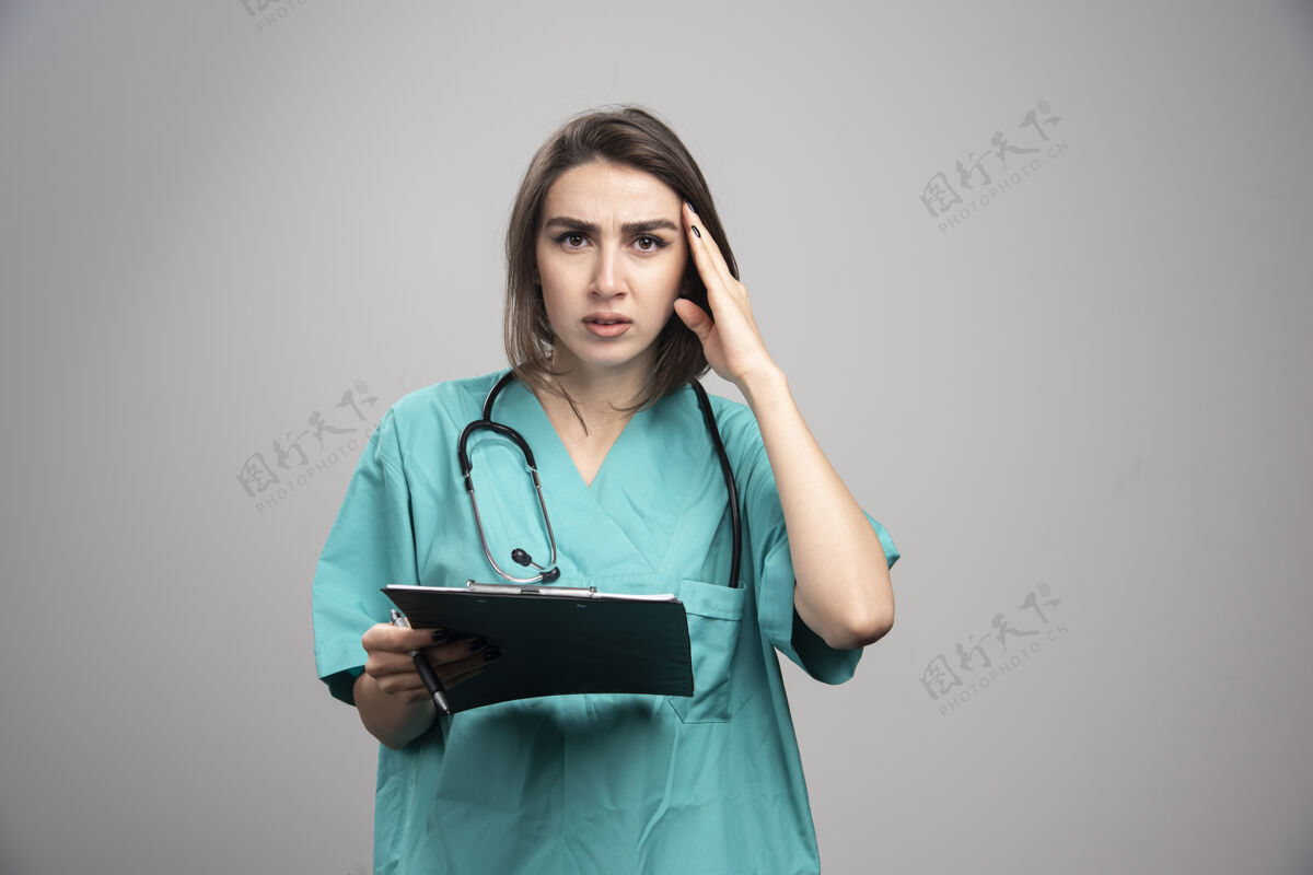 年轻在灰色背景上头痛的年轻医生高质量的照片医生人工作