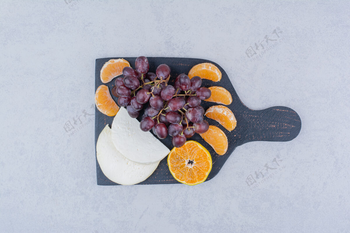 切片一块深色的砧板 上面放着切碎的奶酪和水果切葡萄食物