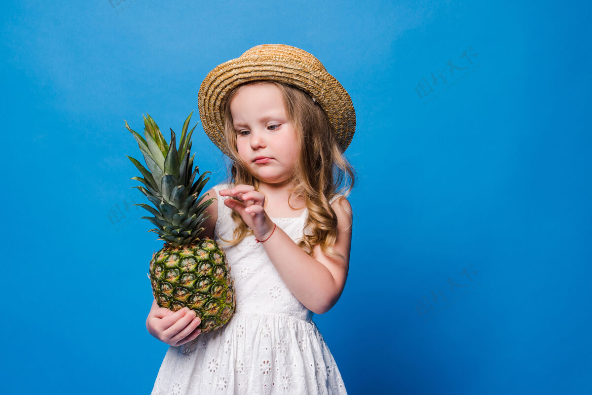 小女孩小女孩拿着整个菠萝放在蓝色的墙上 留着复制空间菠萝女孩漂亮