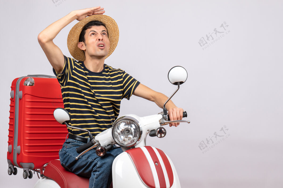 向上骑着轻便摩托车戴草帽的年轻人仰望的正视图摩托车车辆前面