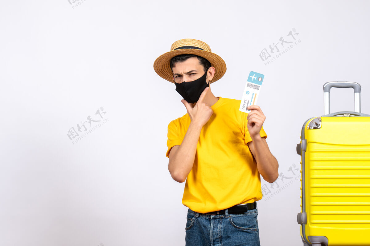 成人正面图：戴着草帽和面具的年轻人站在黄色手提箱旁 手里拿着机票男性持有年轻人