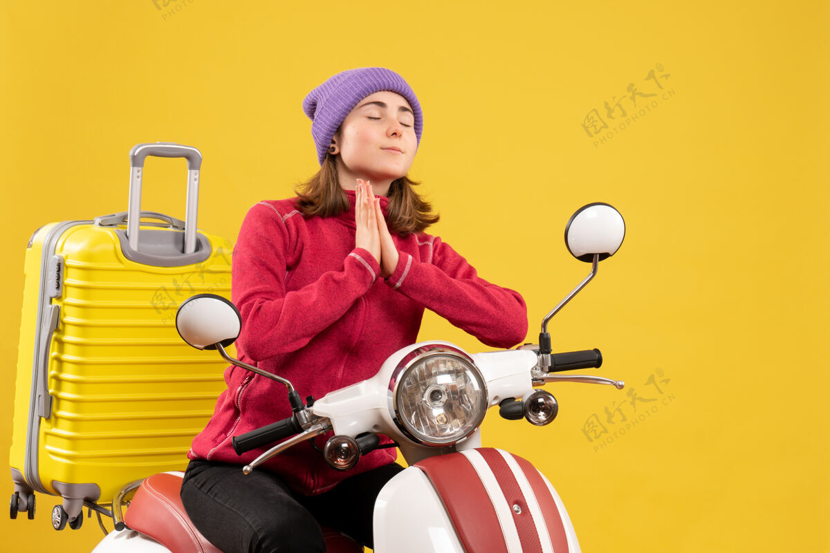成人前视图：坐在轻便摩托车上的年轻女子手牵手祈祷前面年轻女子坐着