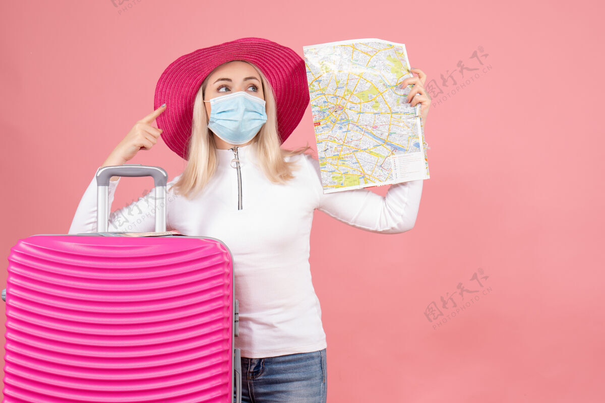 立场前视图年轻女士站在手提箱旁边拿着地图指着什么东西成人地图手提箱