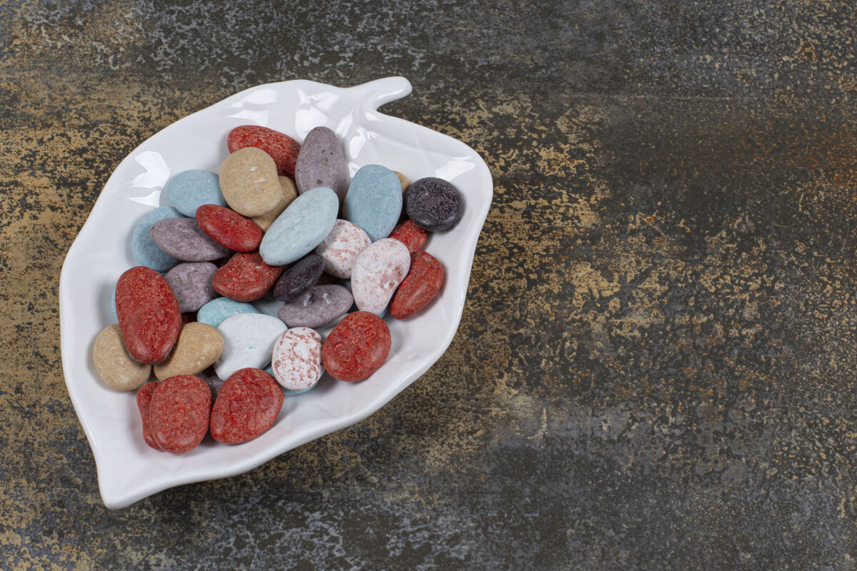 石头椭圆形的石头糖果放在叶子形状的盘子上甜点圆形岩石