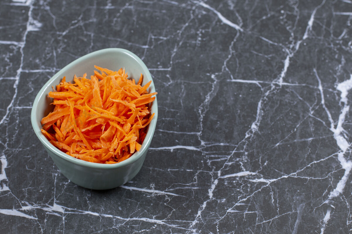 切片把新鲜胡萝卜放在蓝色的陶瓷碗里素食多汁饮食