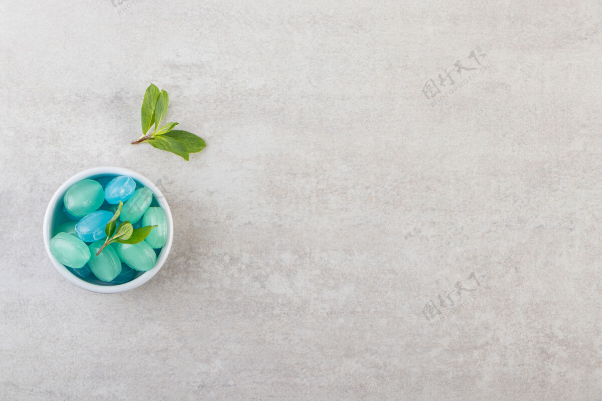 蓝色蓝色和绿色的硬糖在碗里放在石桌上绿色好吃背景