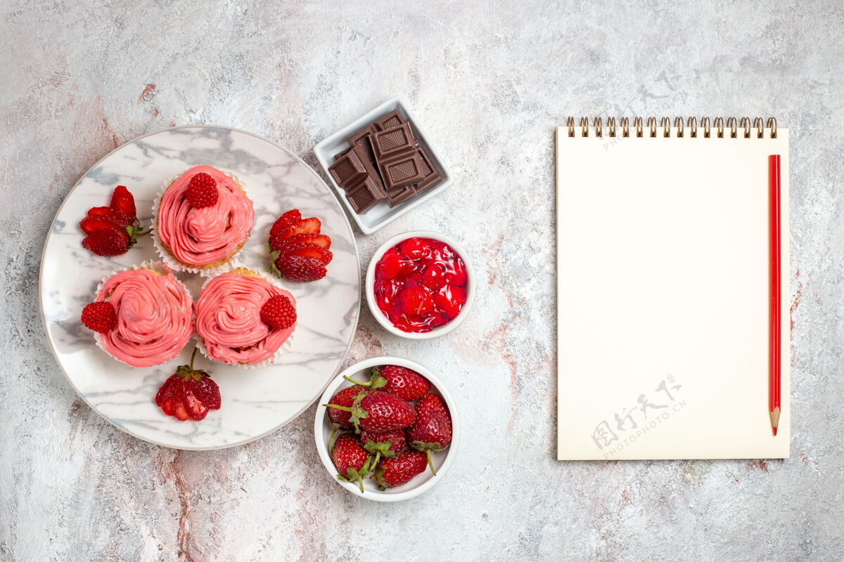 饼干白色表面上有奶油和一杯茶的粉色草莓蛋糕俯视图奶油饼干水果