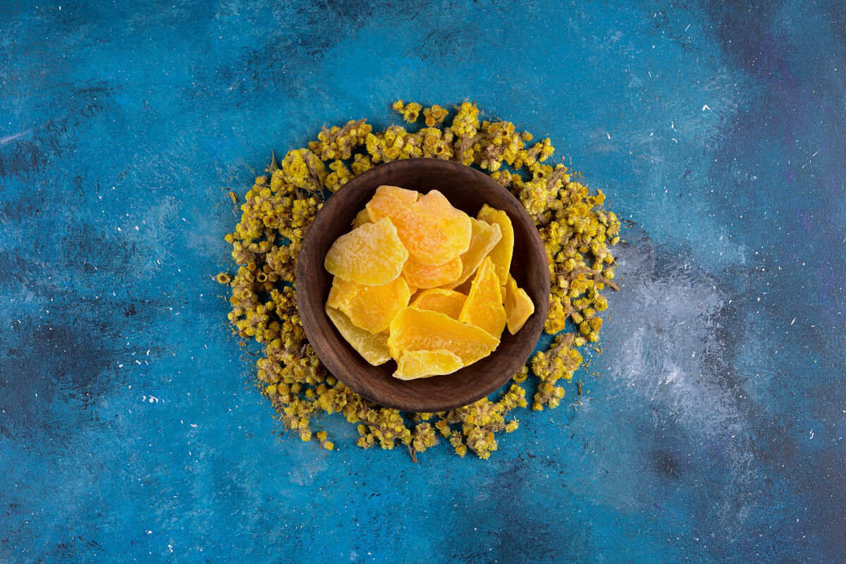 香蓝色桌子上有一束黄色的干花和干果黄花新鲜草药