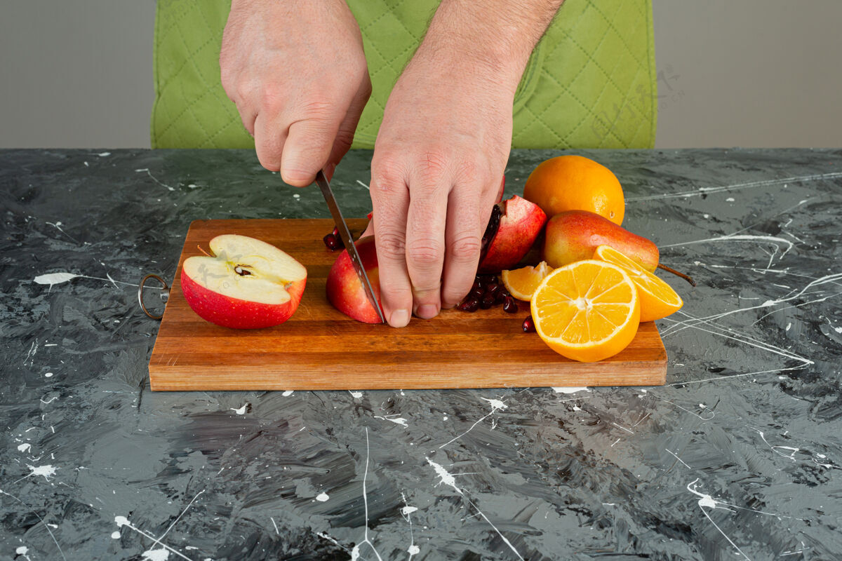 刀男手在桌上的木板上切红苹果烹饪手混合