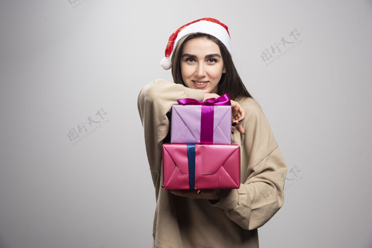 抱着年轻女子在展示两份圣诞礼物站着人礼物