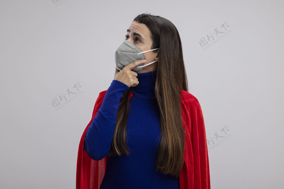 面具印象深刻的年轻超人女孩一边看着戴着医用口罩把手放在下巴下隔离在白色穿着壁板下巴