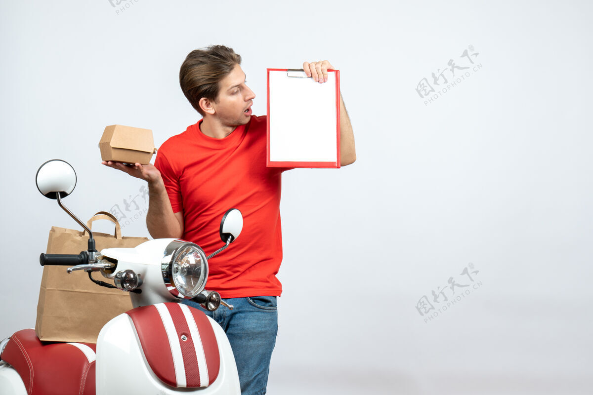 红色顶视图混乱的送货员身穿红色制服 站在滑板车旁 手持订单和文件 背景为白色滑板车站着背景