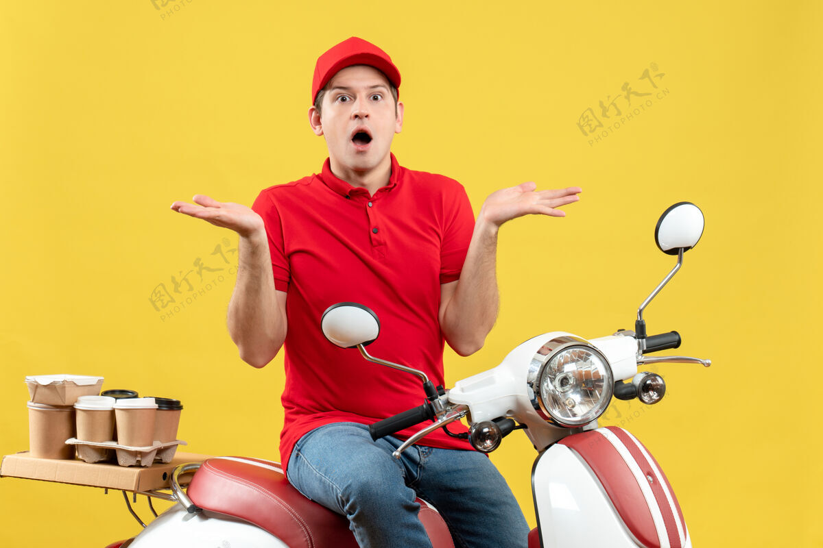 男子一个穿着红色上衣 戴着帽子的年轻人正对着黄色背景 向两边发出命令轻便摩托车年轻人运动