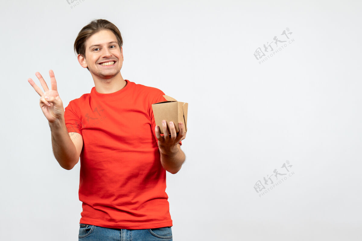 肖像正面图是一个微笑的年轻人 穿着红色上衣 手里拿着一个小盒子 上面有三个白色的背景男孩男性三个