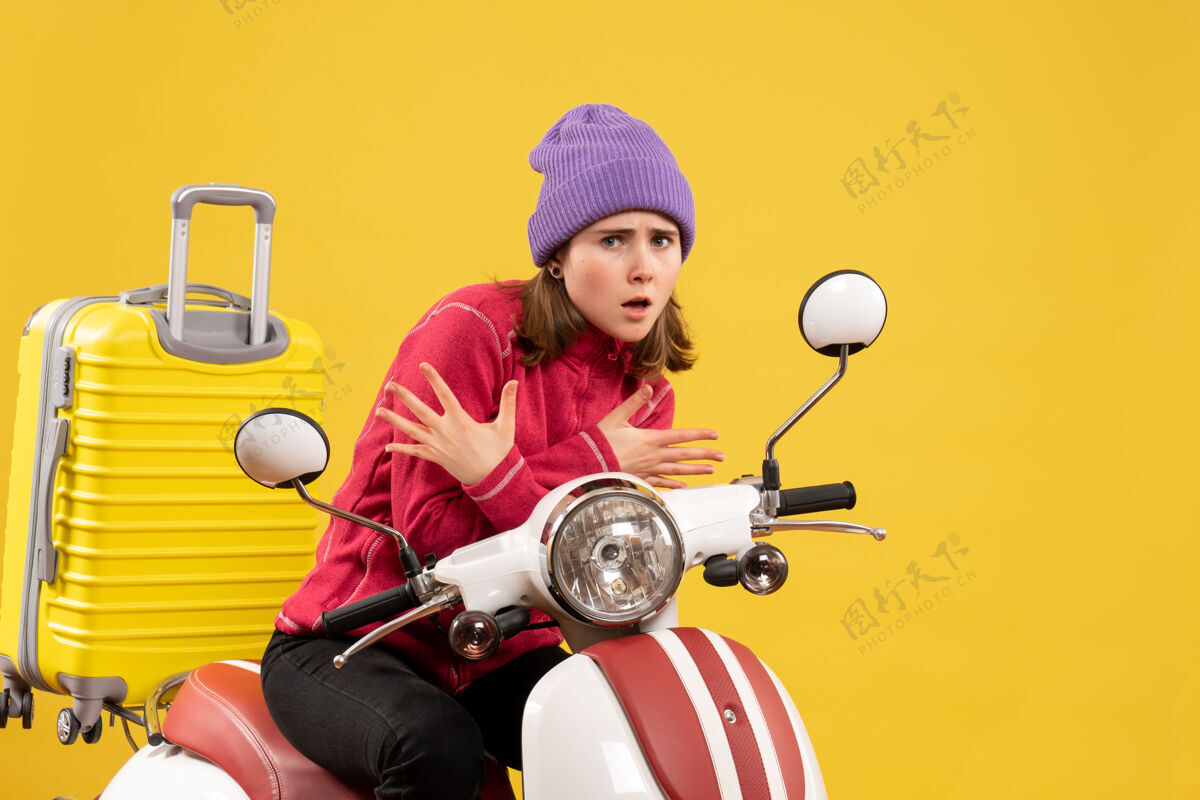 轻便摩托车前视图吓坏了那个戴着紫色帽子骑着轻便摩托车的年轻女孩摩托车吓坏了前面