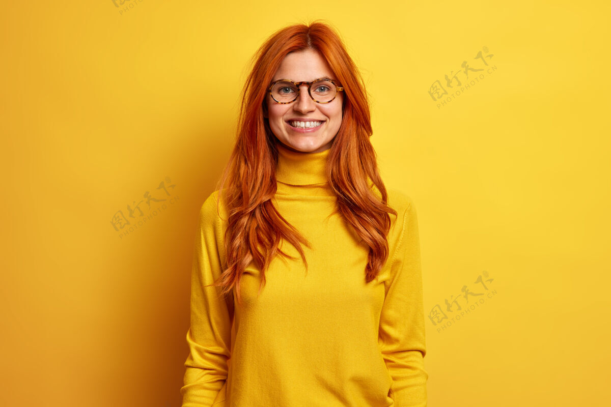 单色快乐微笑的红发女人的画像总是积极的 喜欢和穿着高领毛衣戴着眼镜的朋友谈笑风生漂亮女性年轻