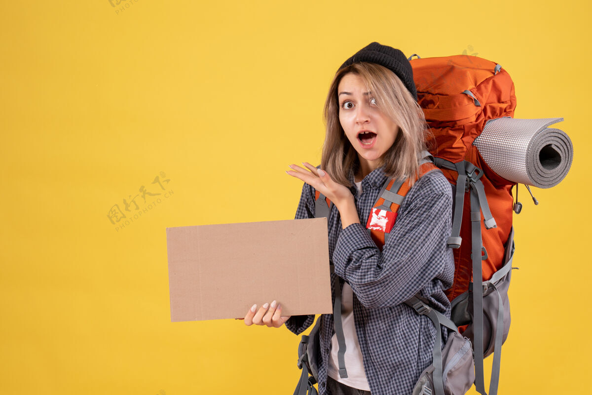 持有前视图惊讶的旅行妇女与背包举行纸板时尚前面人