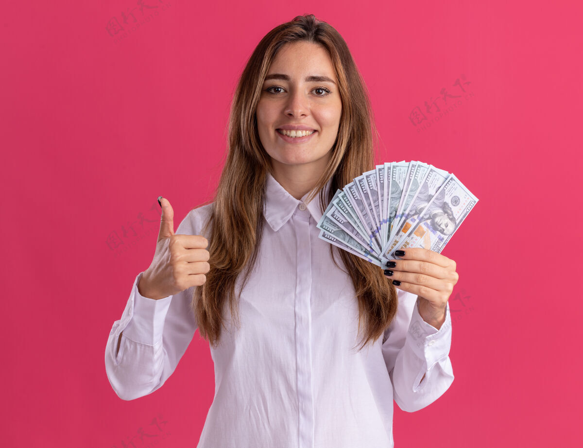 漂亮年轻漂亮的白人女孩微笑着竖起大拇指 手里拿着粉红色的钞票年轻钱模特