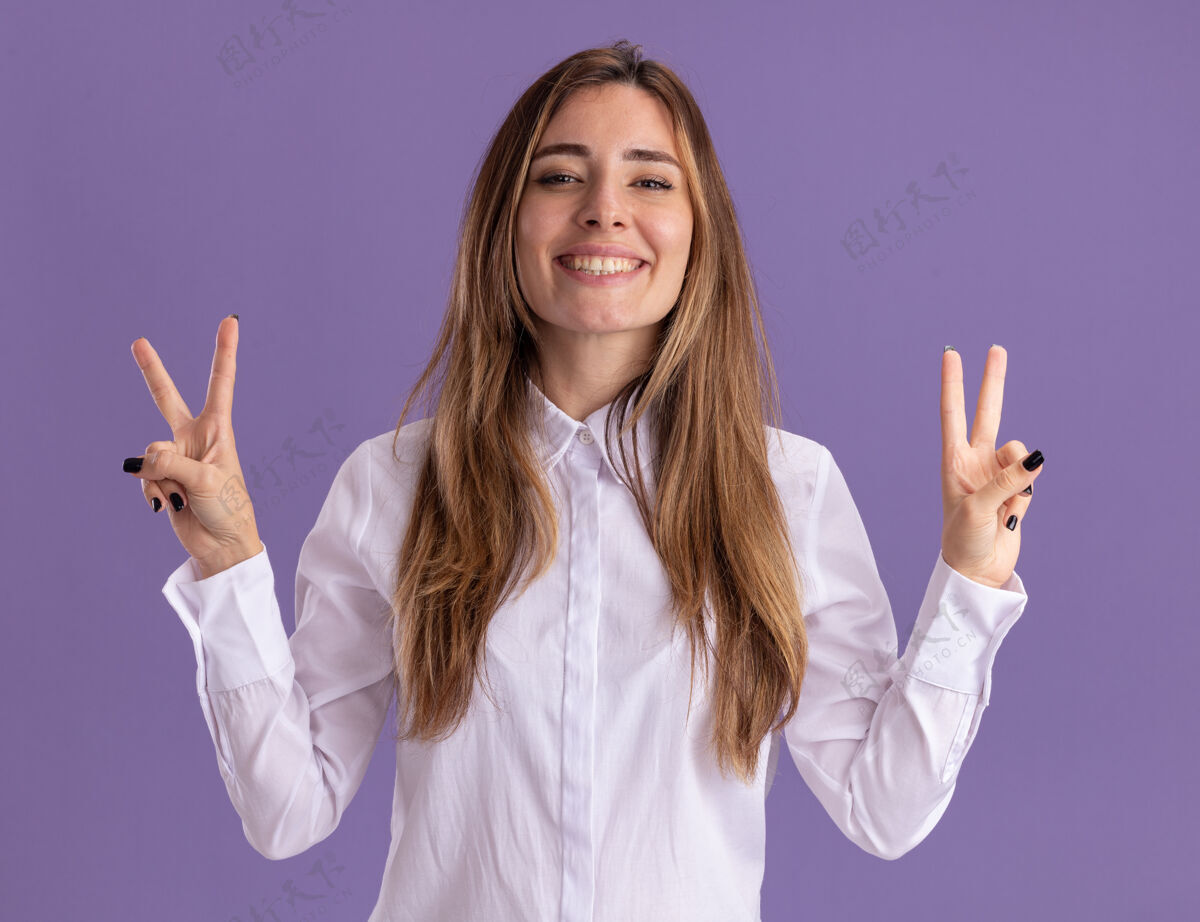 手年轻漂亮的白人女孩微笑着用两只手指着紫色的胜利标志胜利女孩标志