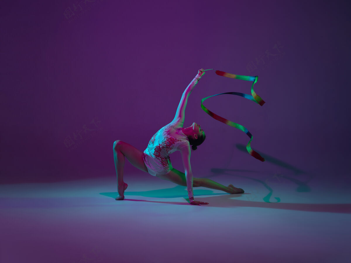优雅年轻的女运动员 艺术体操艺术家 舞蹈 在紫色的霓虹灯背景下孤立训练美丽的女孩用设备练习优雅的表演灵活表演活动