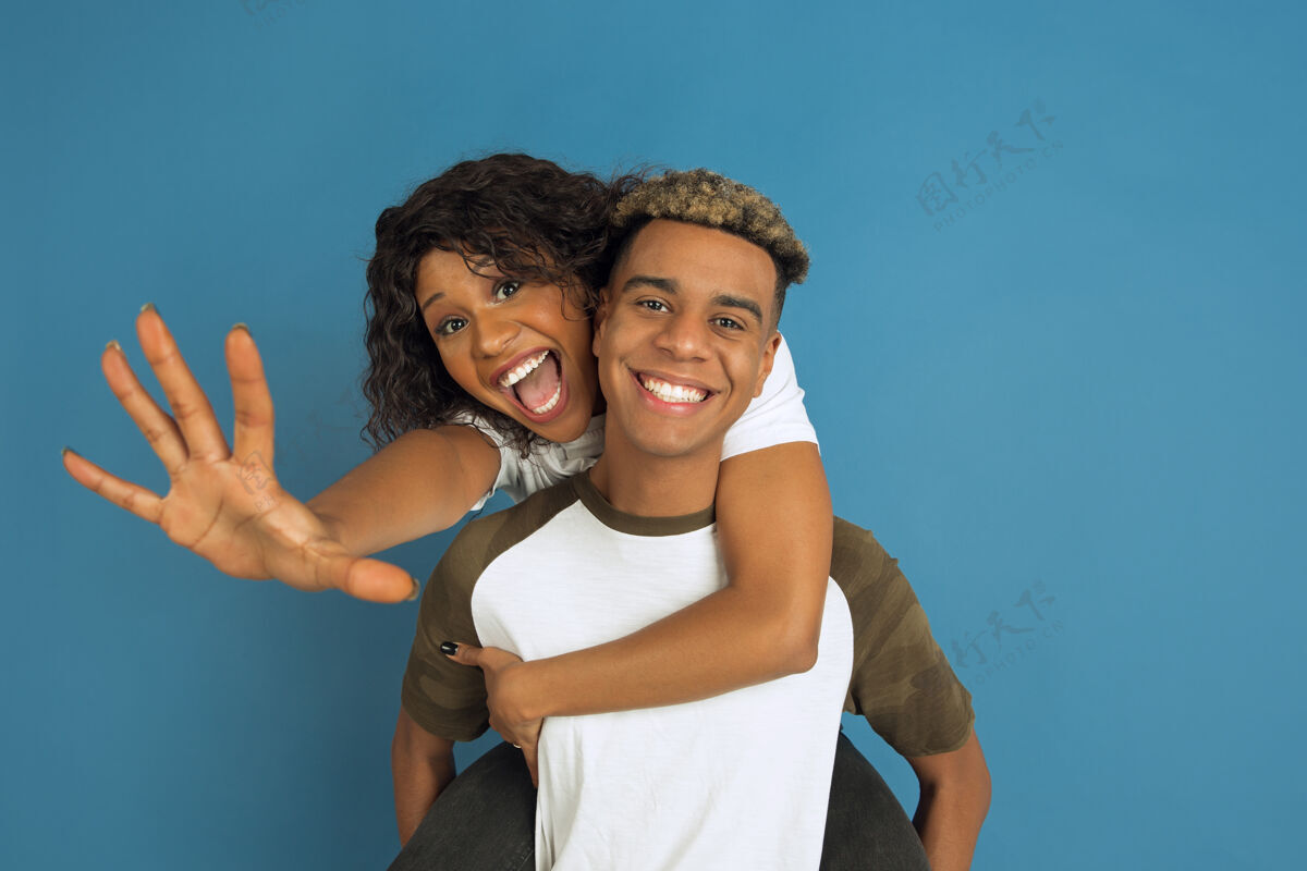 化妆年轻感性的非裔美国人 穿着白色休闲服 在蓝色背景上摆姿势美丽的情侣人类情感的概念 面部表情 关系 广告拥抱 大笑金融女性微笑
