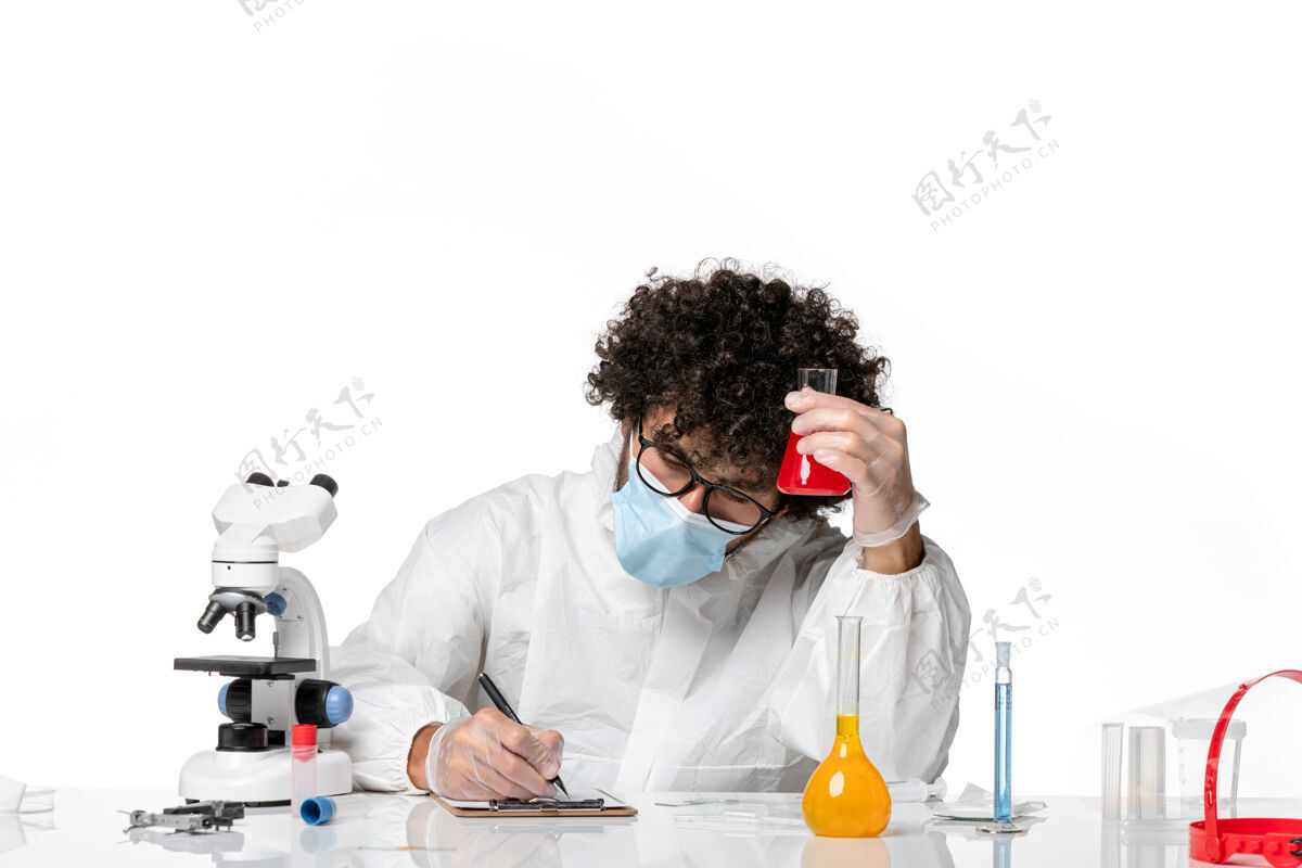 男医生正面图：男医生穿着防护服 戴着口罩 拿着一个装有红色溶液的烧瓶 在白色背景上写着大流行性冠状病毒-流行性病毒白色口罩防护