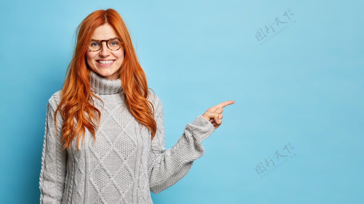 成人一位戴着眼镜的欧洲红发女士开朗地微笑着 指着复印件上的空白处指点着最好的一家冬天穿暖和毛衣的商店展示快乐请