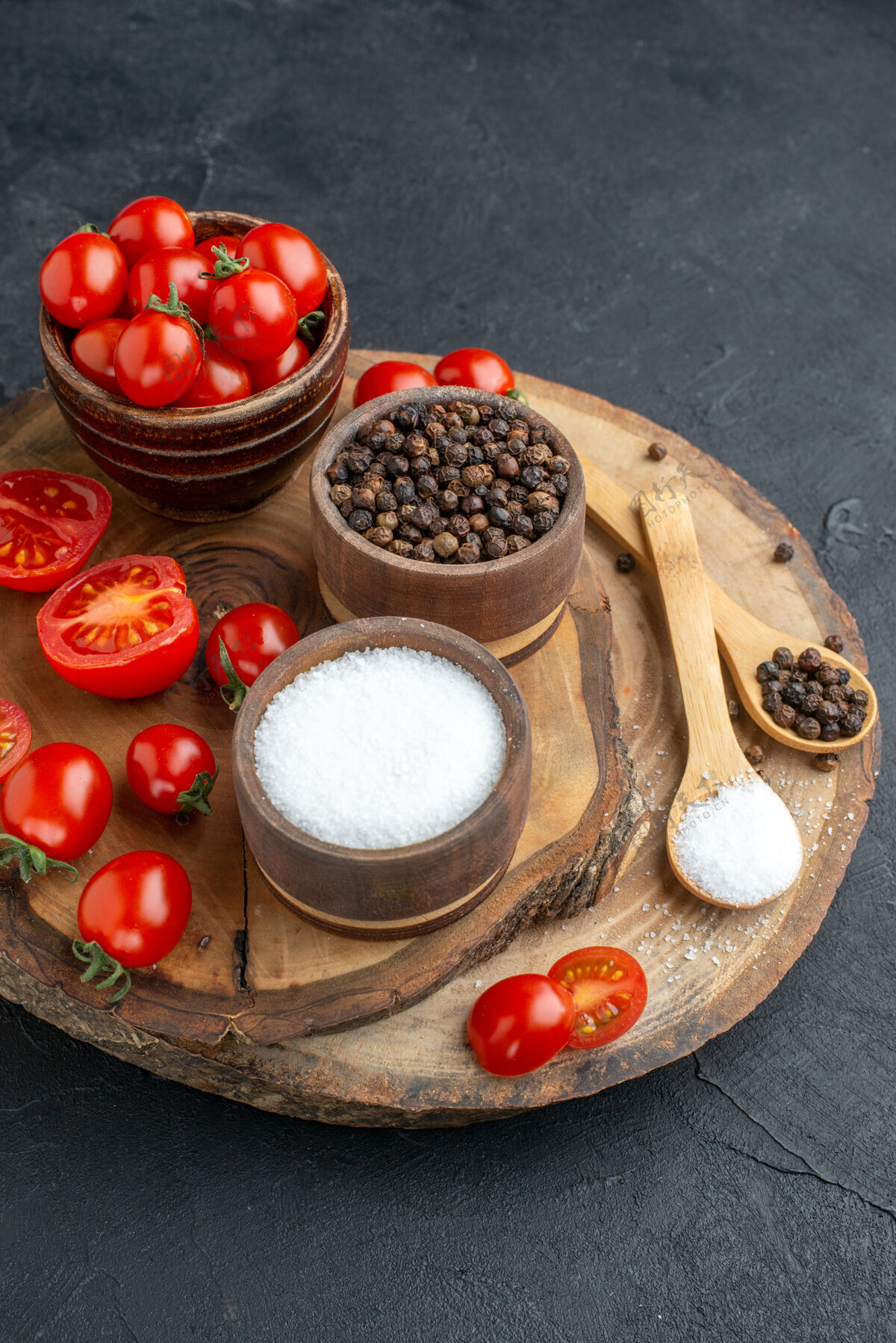 板新鲜西红柿和香料的顶视图在碗里勺子在木板上的黑色表面健康食物樱桃