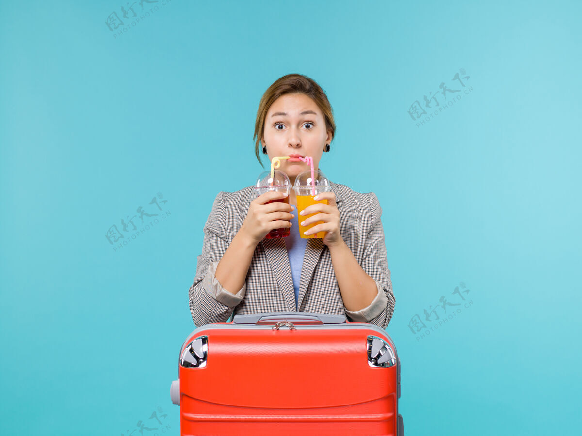 举行前视图度假女性手持新鲜饮料在蓝色背景海上旅行度假飞机人女人肖像