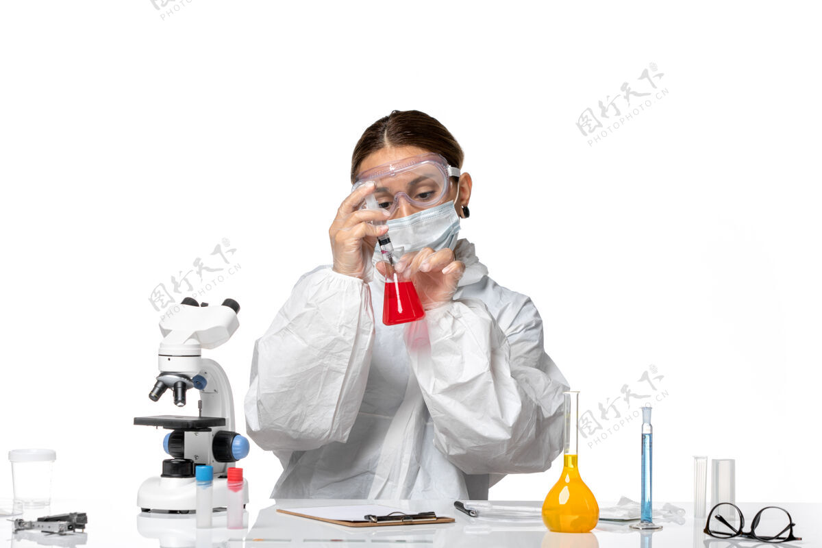 流行病正面图：穿着防护服 戴着口罩的女医生正在用白色办公桌病毒大流行冠状病毒的解决方案工作工作套装商务