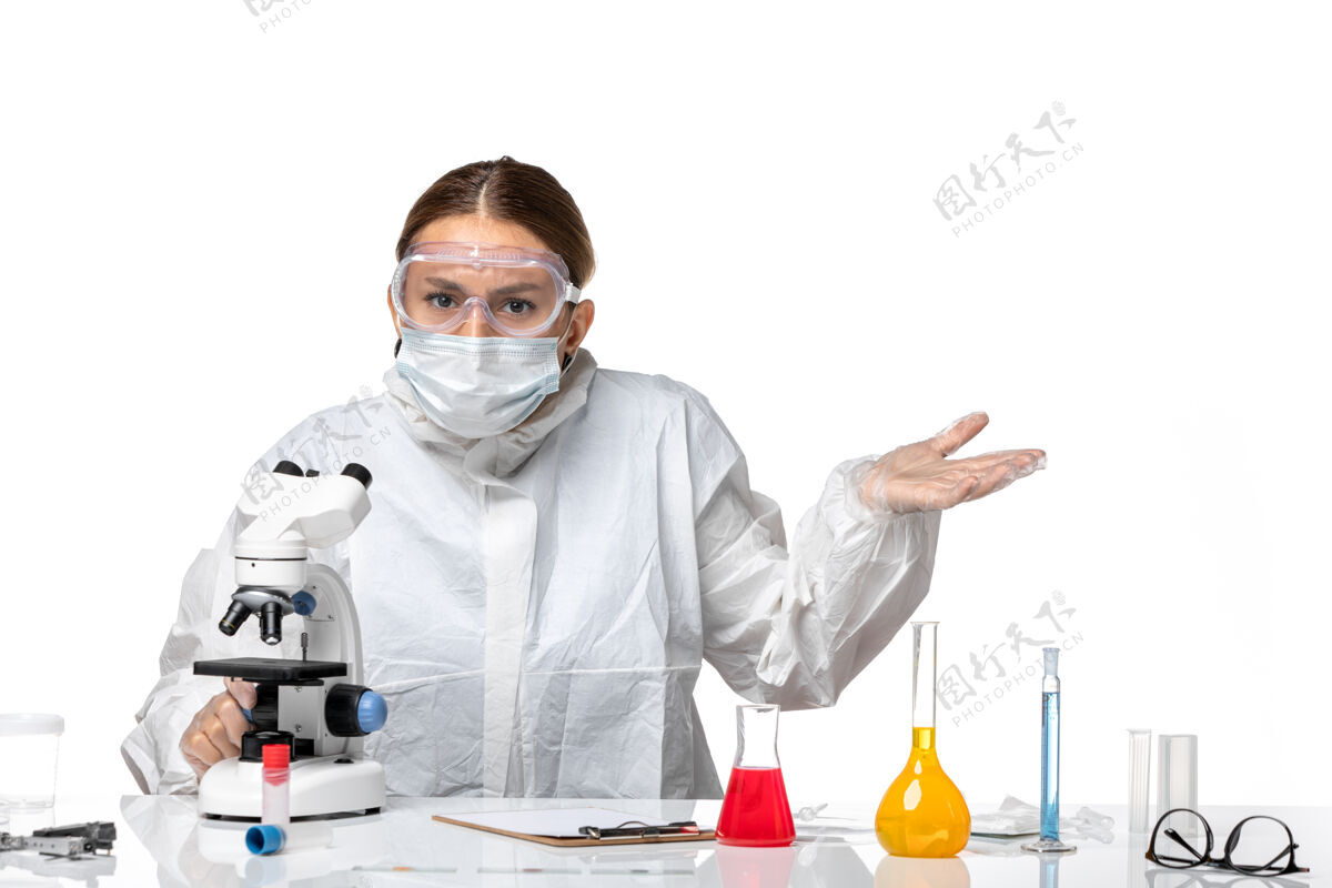 病毒正面图女医生穿着防护服 戴着口罩 用显微镜对白色背景卫生大流行病毒冠状病毒视图药品实验室外套
