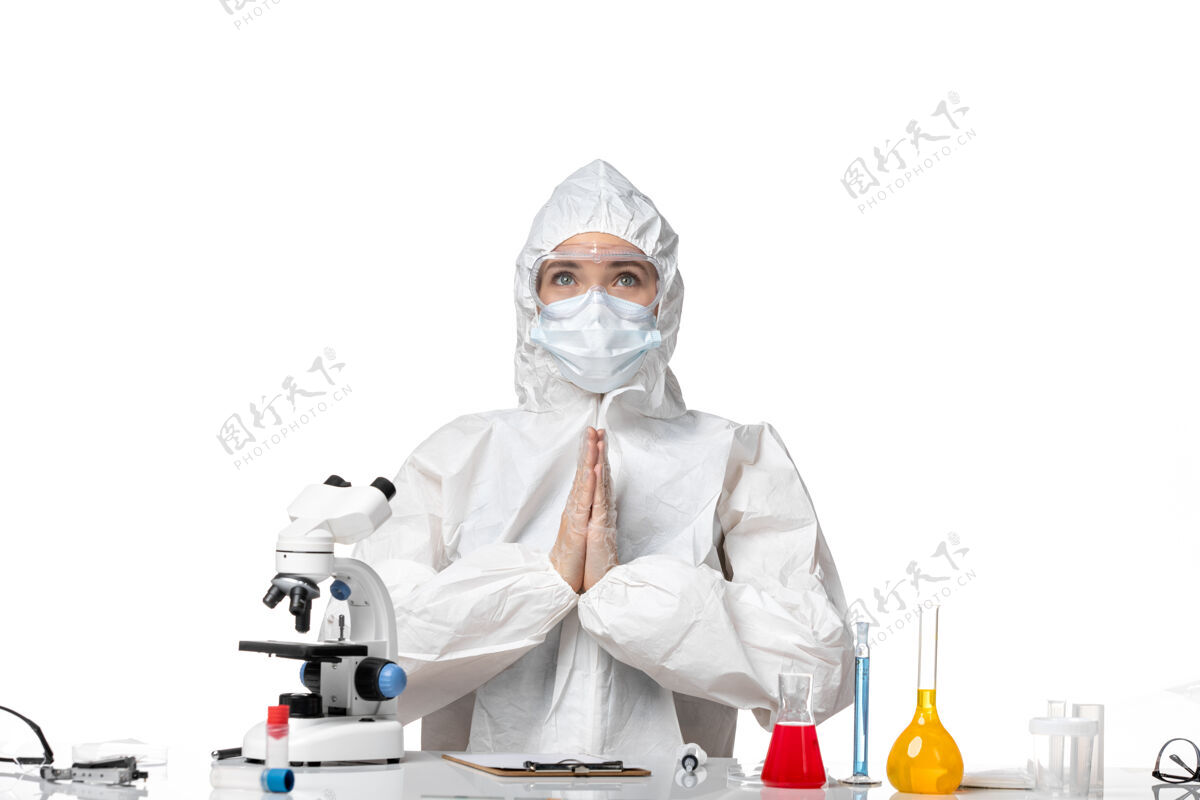 视图正面图女医生穿着防护服 戴着口罩 由于柯维德坐在白色背景上病毒大流行飞溅柯维德-前面西装神秘