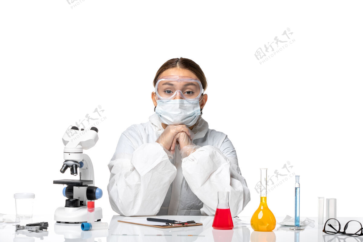 药正面图：女医生穿着防护服 戴着口罩 坐在白色背景上 用解决病毒的药水预防健康大流行套装坐着女医生