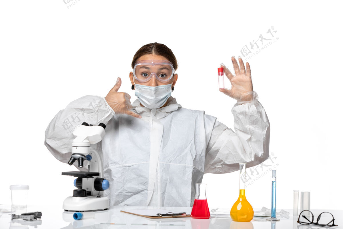 空正面图女医生穿着防护服 戴着口罩 拿着淡白色背景上的空烧瓶大流行病毒冠状病毒冠状病毒药物实验室外套健康