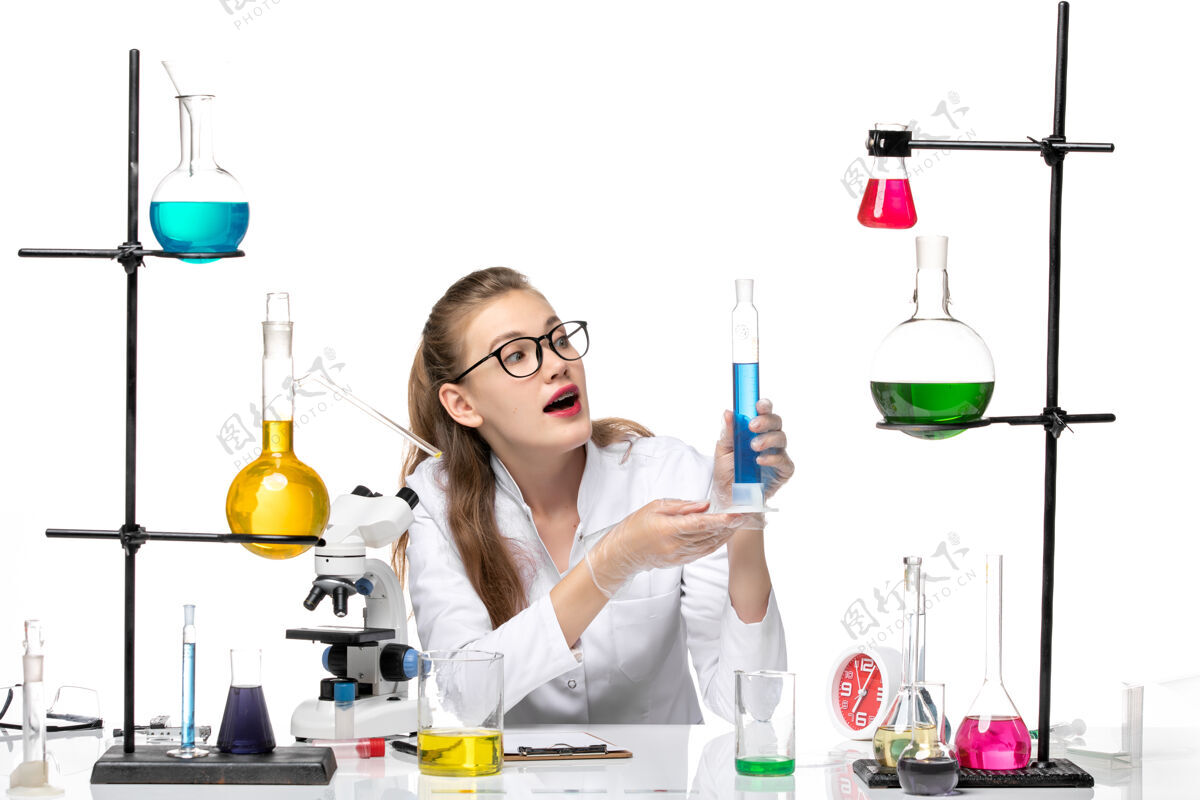 女化学家前视图穿着医疗服的女化学家拿着长烧瓶 白色背景上有溶液化学大流行健康病毒医疗液体查看