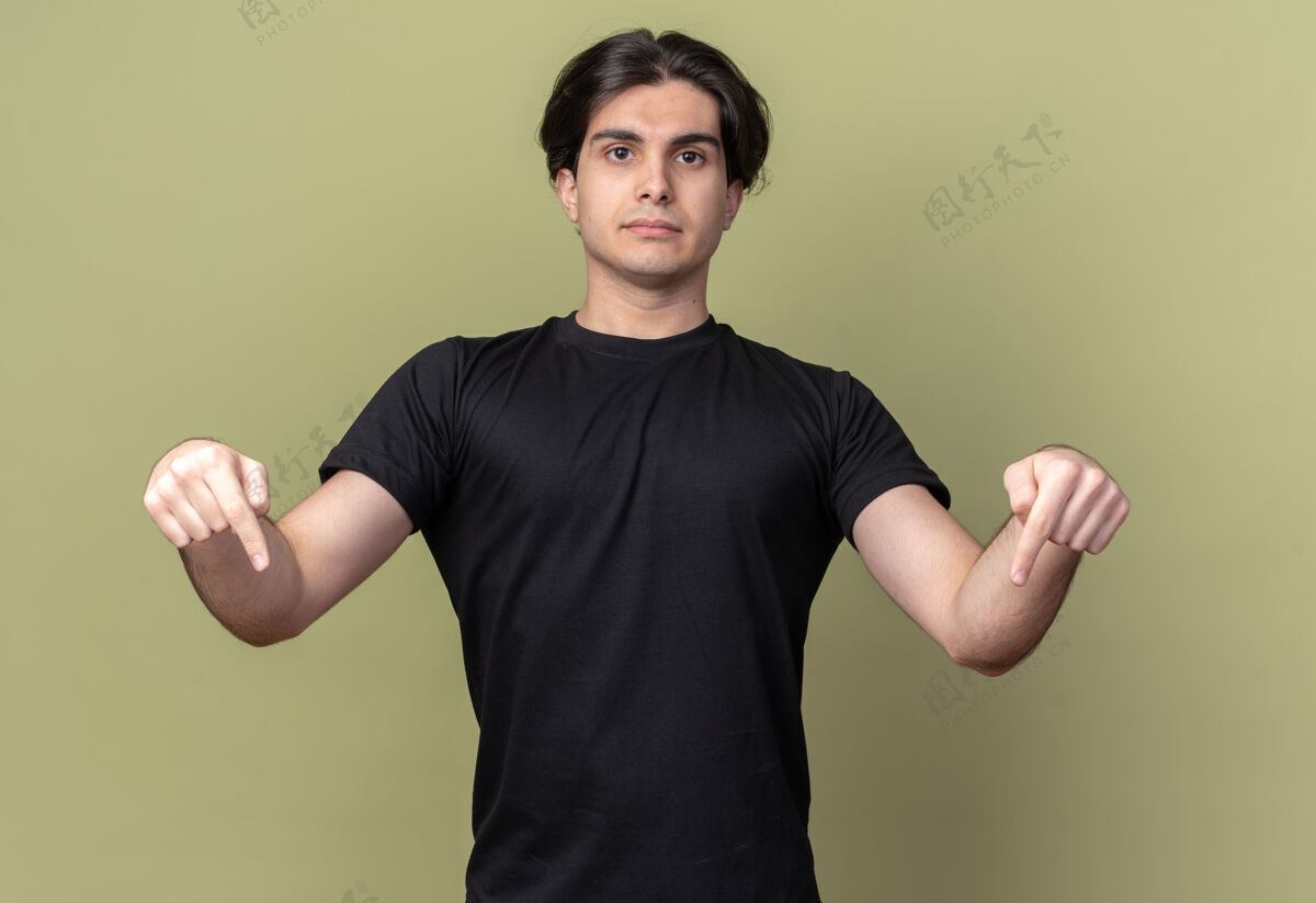 人年轻帅哥穿着黑色t恤点着严厉地落在橄榄绿的墙上站穿着姿势