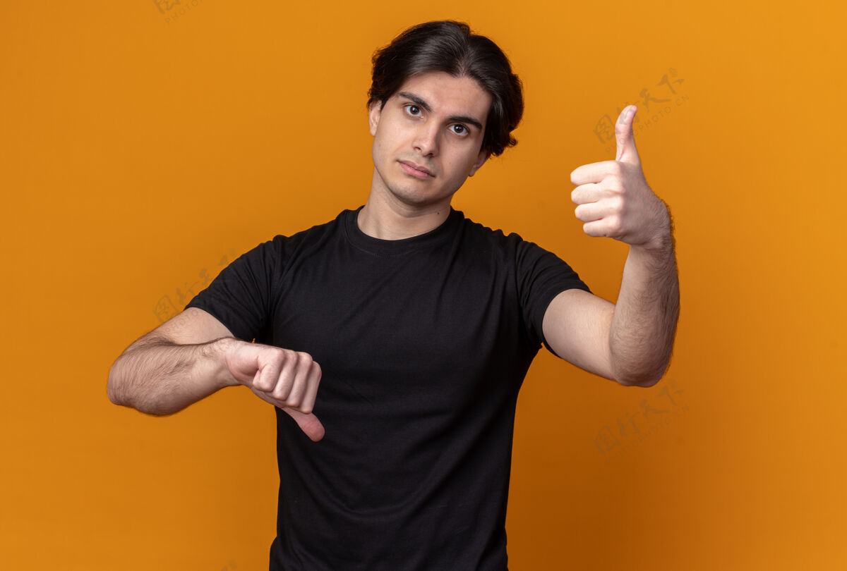 衣服看着前面的年轻帅哥穿着黑色t恤 竖起大拇指 孤立地站在橙色的墙上感觉帅哥穿