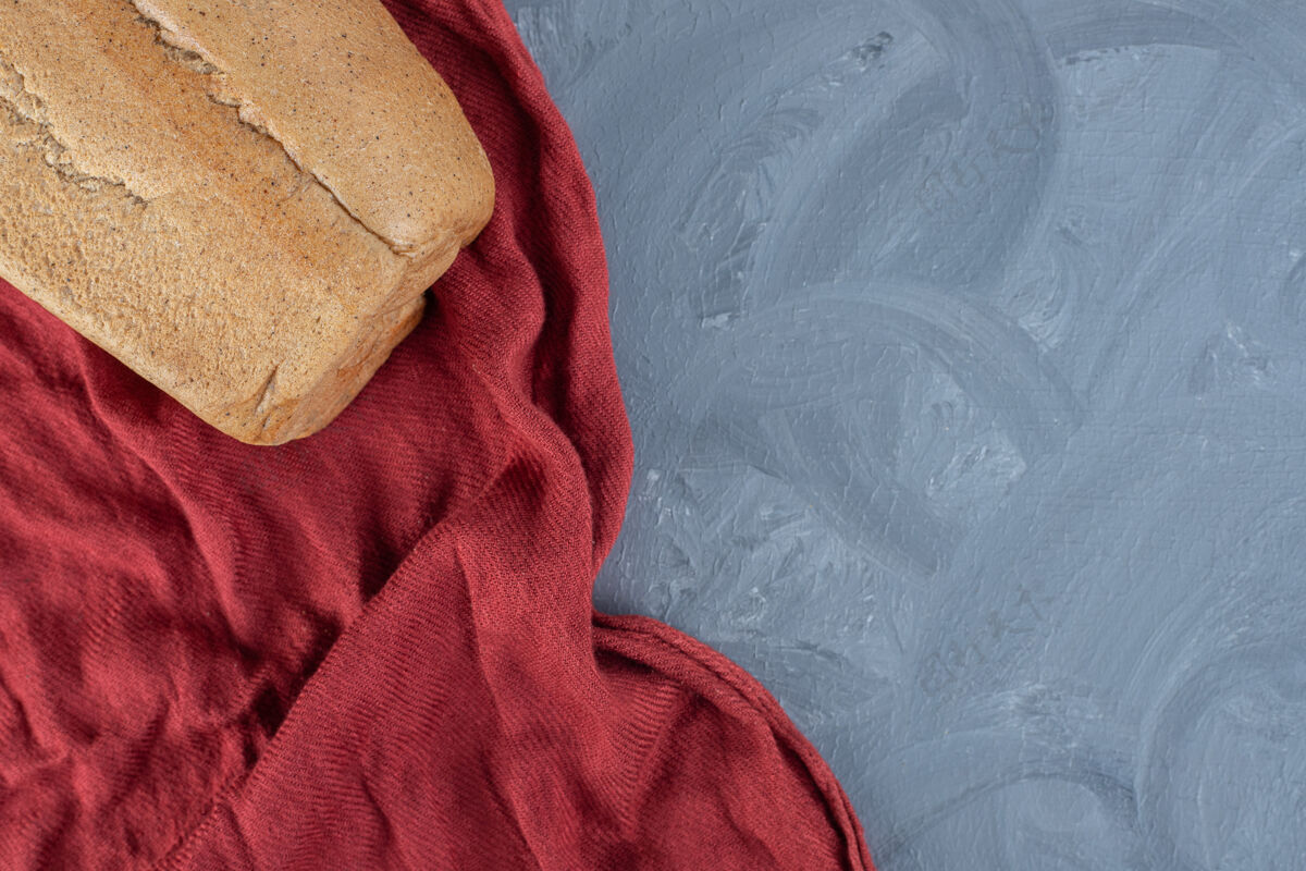美味一块面包放在大理石桌上起皱的红桌布上顶视图桌布可口