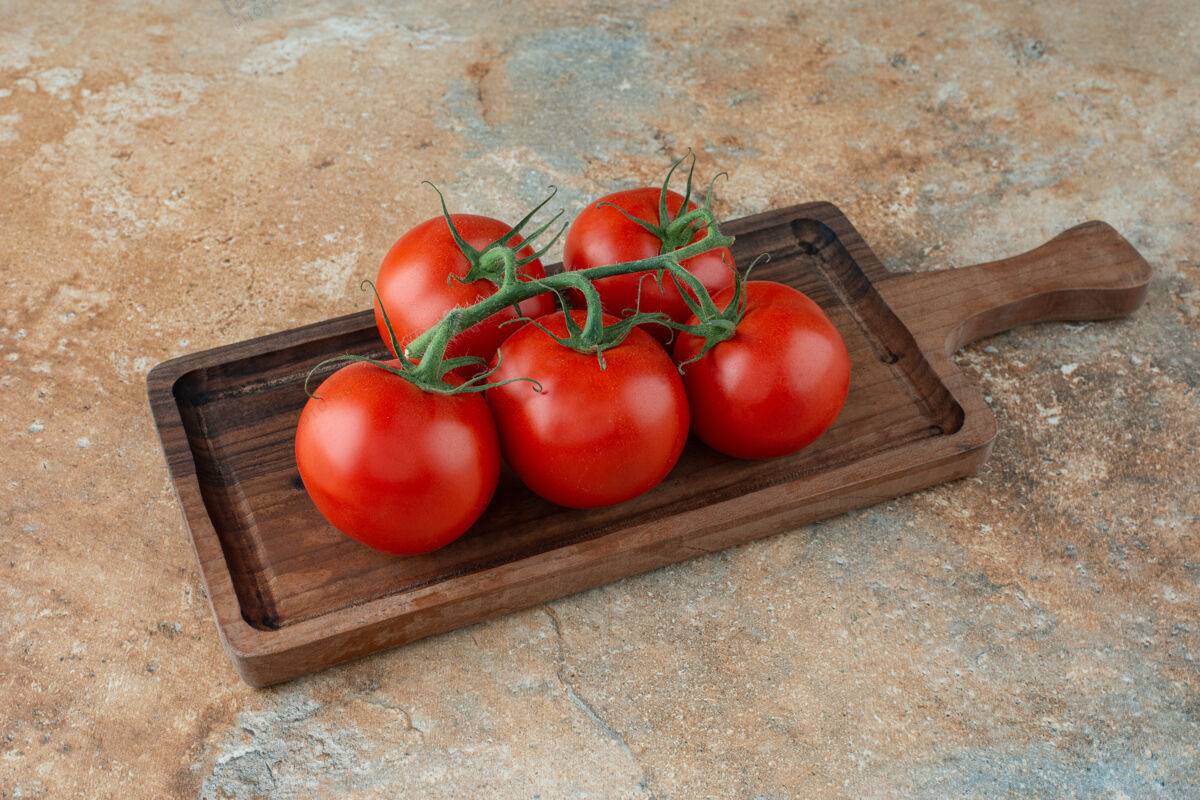 西红柿大理石桌上放着一块放着新鲜西红柿的木板板食物蔬菜