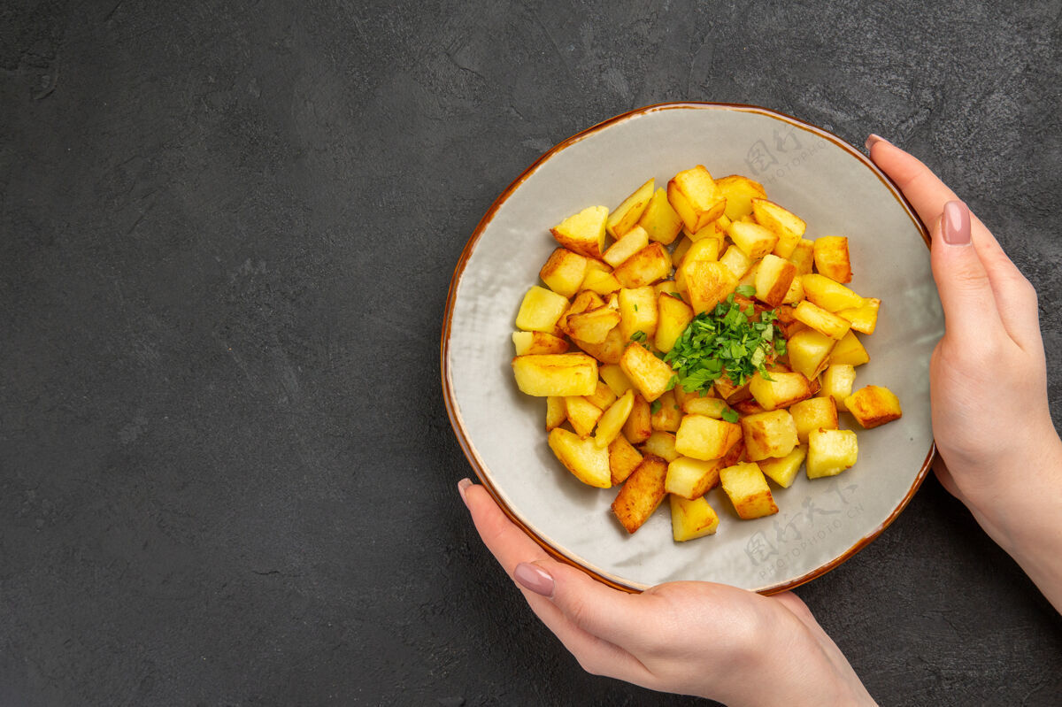地方美味的炸土豆在黑暗的表面与绿色盘子里俯瞰玉米里面晚餐
