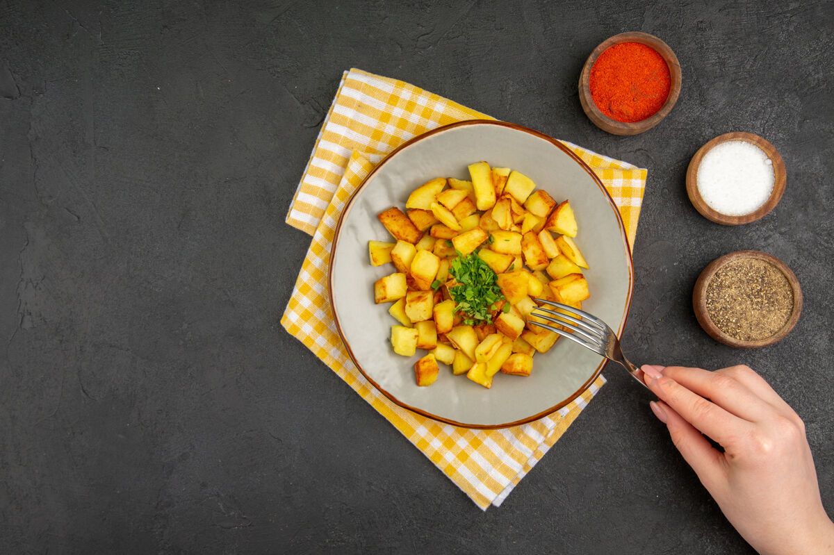 金橘美味的炸土豆顶视图在深灰色的表面与调味品盘子里营养农产品健康