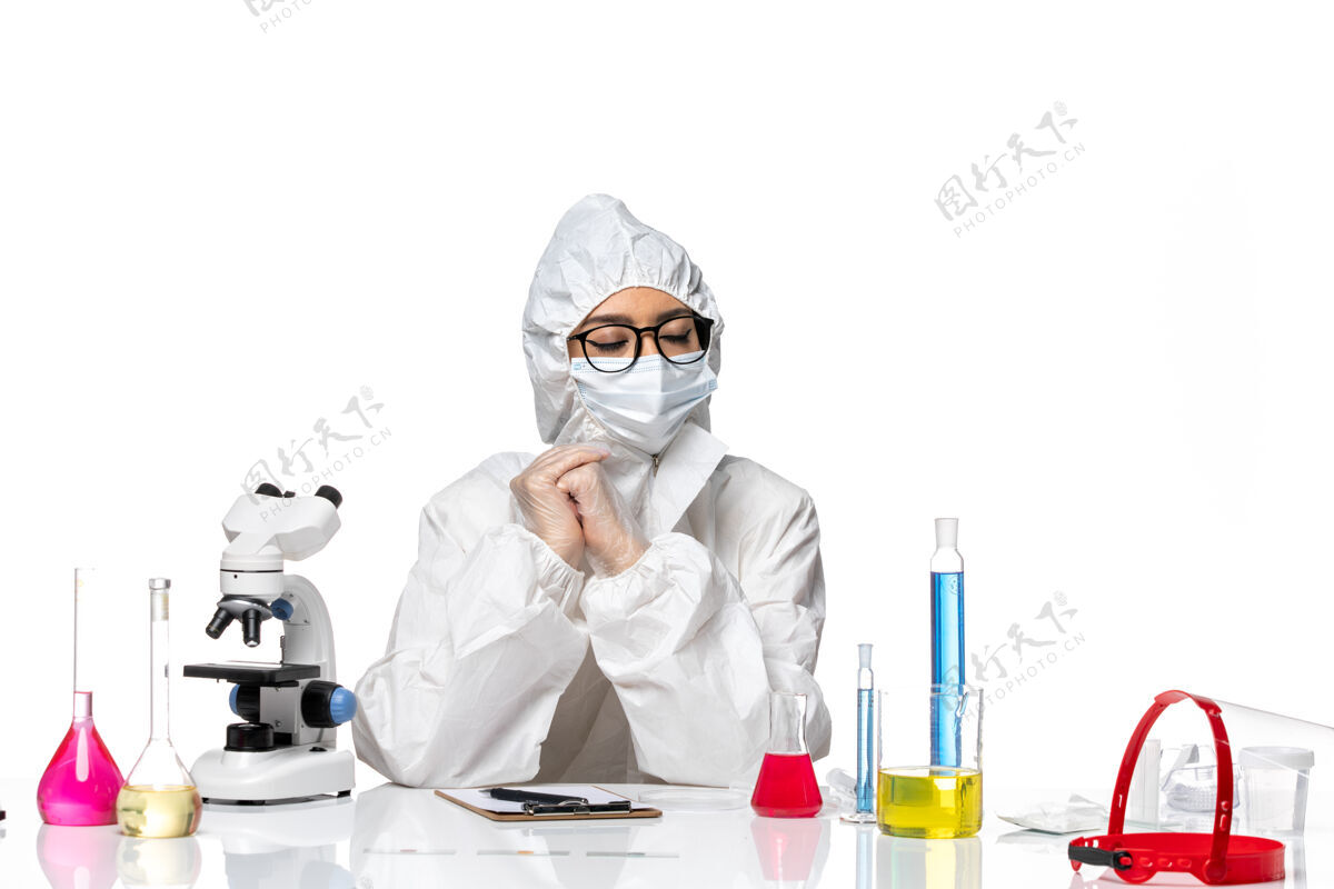 化学前视图穿着特殊防护服的女化学家坐在浅白背景上 解决化学冠状病毒大流行病毒医生坐着