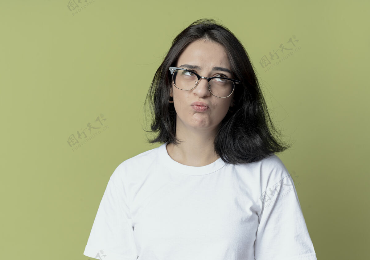 年轻体贴的年轻漂亮的白人女孩戴着橄榄绿背景的隔离眼镜看着侧面壁板背景橄榄
