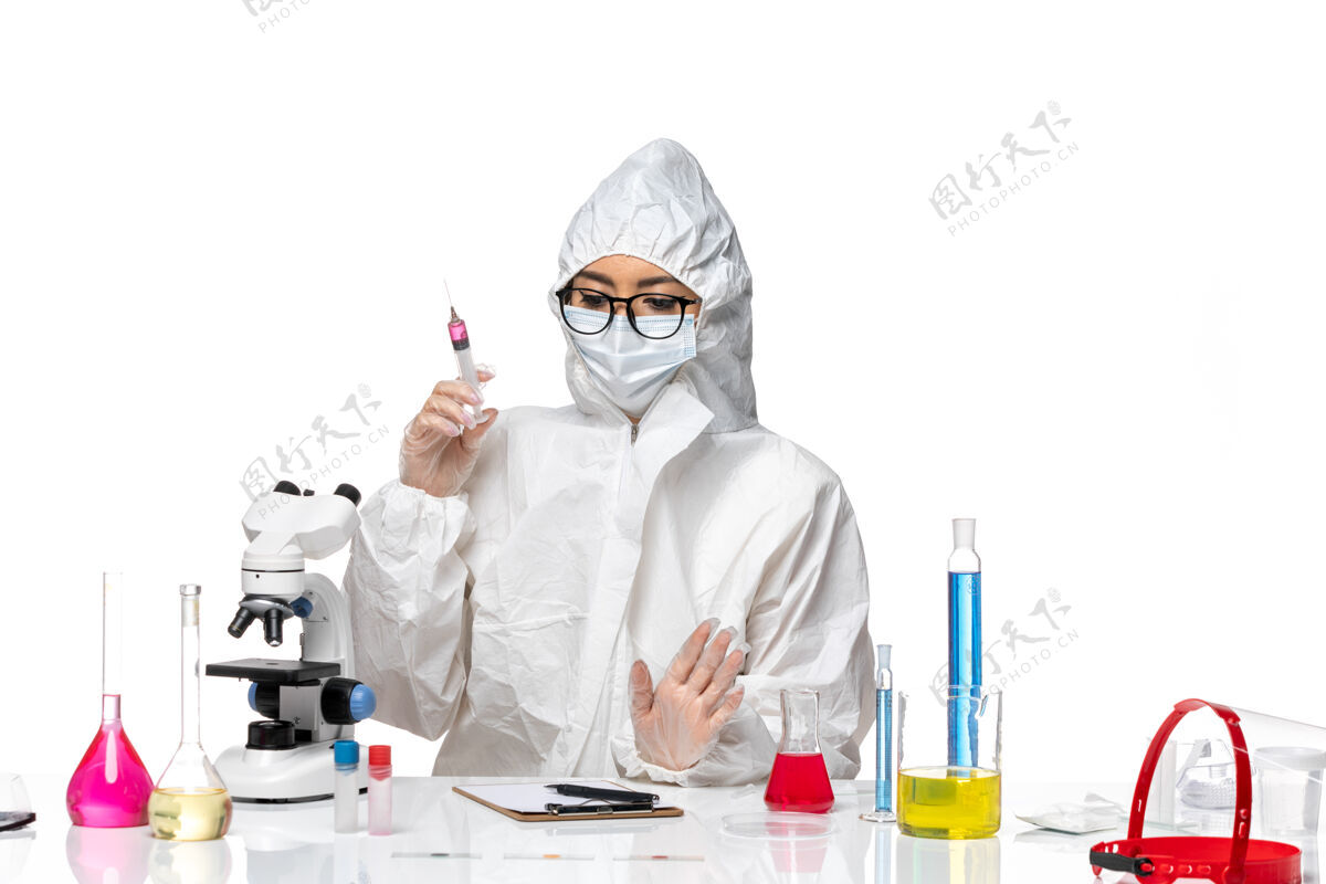 病毒正面图：穿着特殊防护服的女化学家在白色办公桌上注射化学病毒防护视图实验室